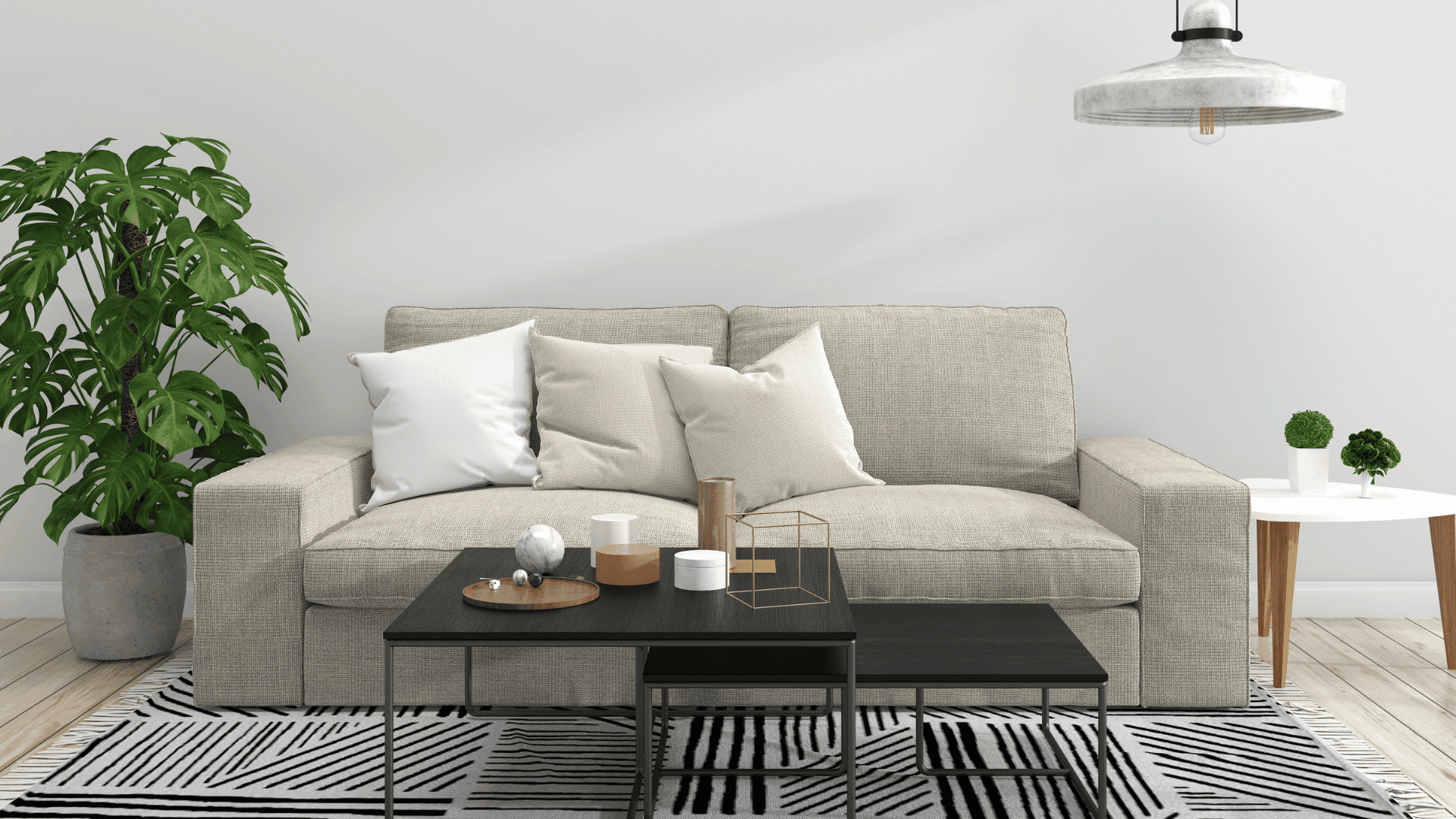 A living room with a beige couch with throw pillows, a black coffee table, a white side table, a plant, and a black and white striped rug. 
